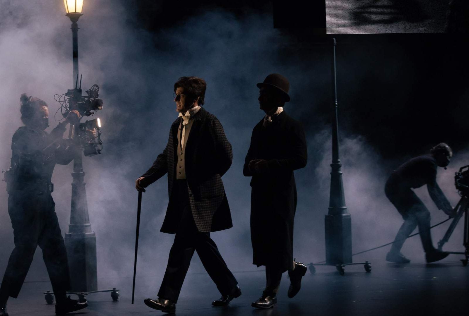 Matthew Backer and Ewen Leslie in Sydney Theatre Company's 'Strange Case of Doctor Jekyll and Mr Hyde.' They walk through fog, in Victorian-era clothing with two videographers following them with cameras.