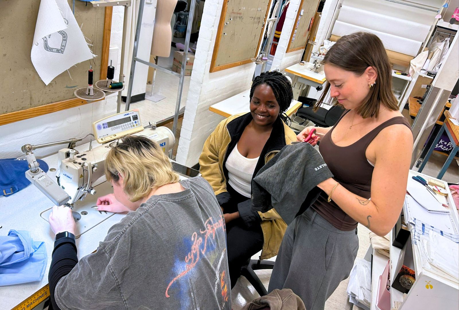 Three NIDA students in the costume 3 classroom mending their clothes.