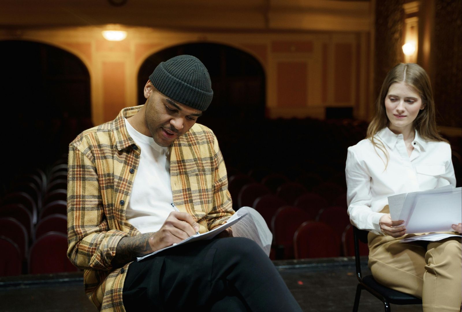 Two writers are sitting as part of a group discussion working on their manuscripts.